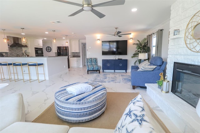 living area with visible vents, marble finish floor, recessed lighting, a fireplace, and crown molding