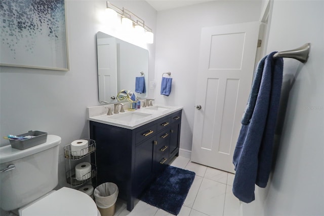 bathroom with double vanity, toilet, and a sink