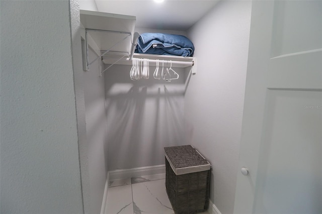 walk in closet featuring marble finish floor