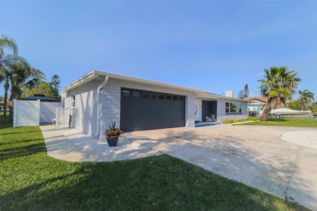 view of front of home with a front lawn, fence, concrete driveway, stone siding, and an attached garage