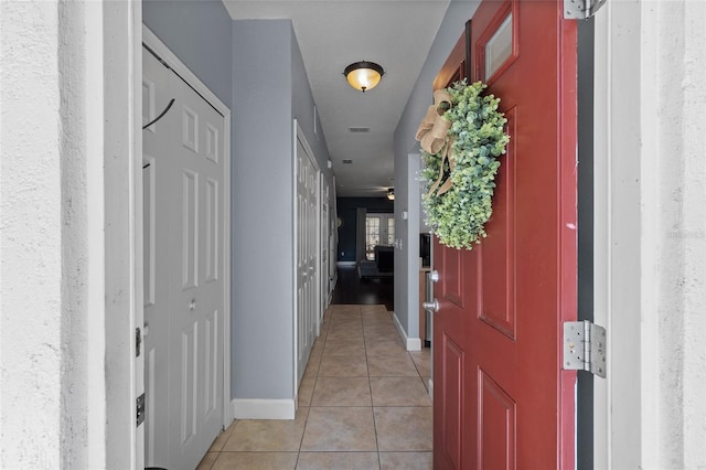 hallway featuring light tile patterned floors, visible vents, and baseboards