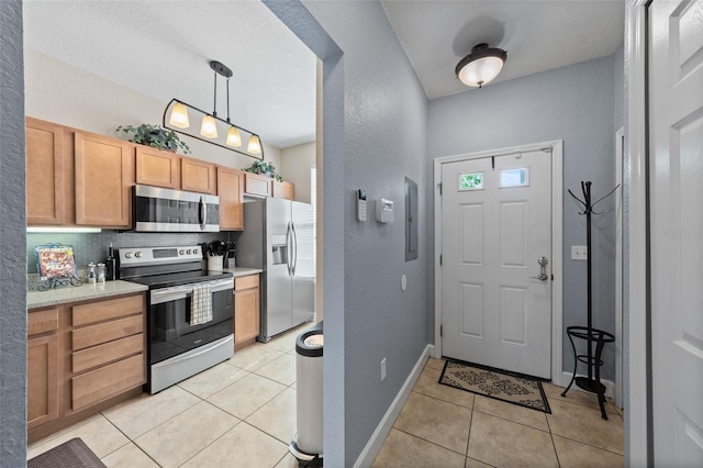 kitchen featuring light tile patterned flooring, backsplash, appliances with stainless steel finishes, and light countertops