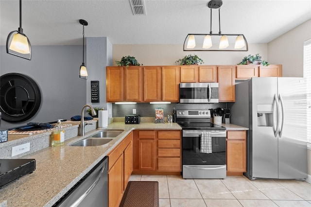 kitchen featuring visible vents, light stone counters, light tile patterned flooring, stainless steel appliances, and a sink