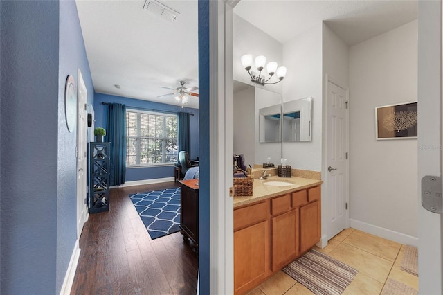 bathroom with visible vents, wood finished floors, baseboards, ceiling fan, and vanity