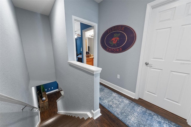 hallway featuring dark wood-type flooring and baseboards