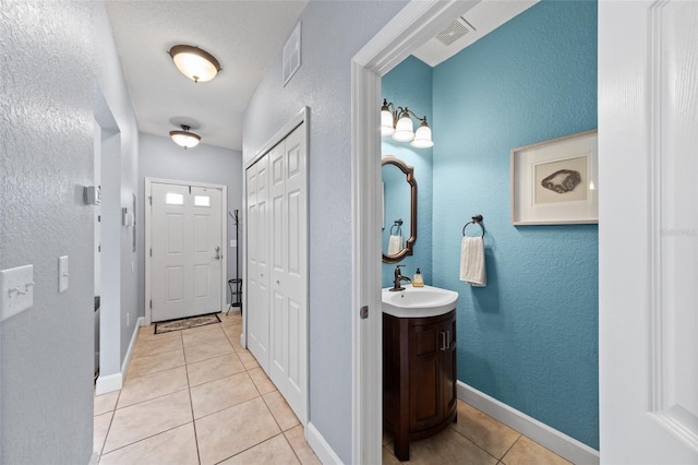 interior space with light tile patterned floors, visible vents, baseboards, and a sink