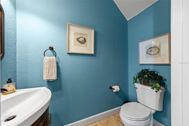 bathroom featuring tile patterned floors, toilet, baseboards, vanity, and a textured wall