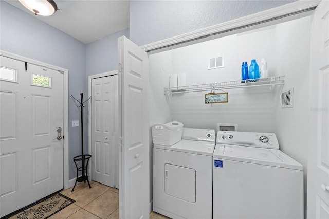 washroom with washing machine and clothes dryer, laundry area, visible vents, and light tile patterned floors