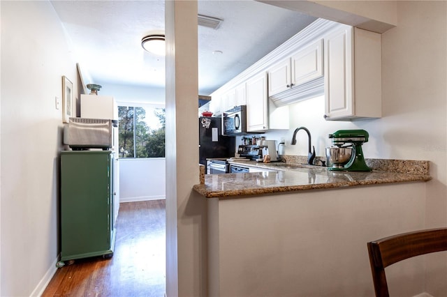 kitchen featuring stainless steel electric stove, stone counters, wood finished floors, white cabinets, and a sink