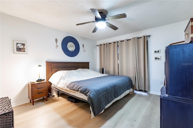 bedroom featuring a textured ceiling, light wood-type flooring, and baseboards