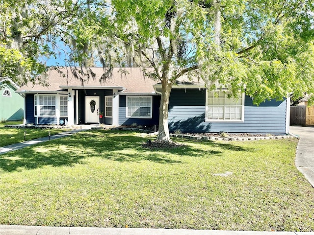 ranch-style house featuring a front lawn and fence