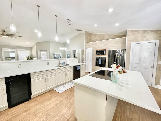 kitchen featuring a spacious island, a sink, black appliances, wine cooler, and light wood-style floors