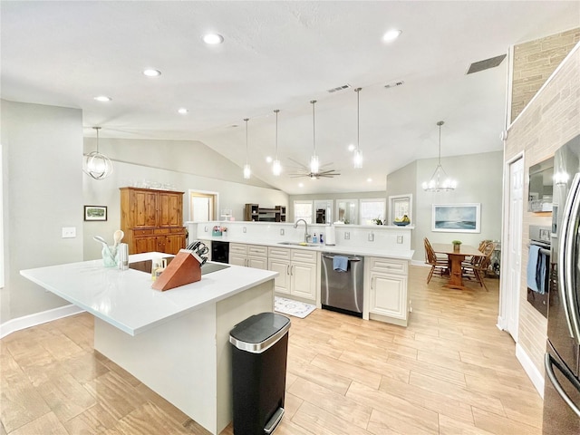 kitchen with a spacious island, light countertops, lofted ceiling, appliances with stainless steel finishes, and a sink