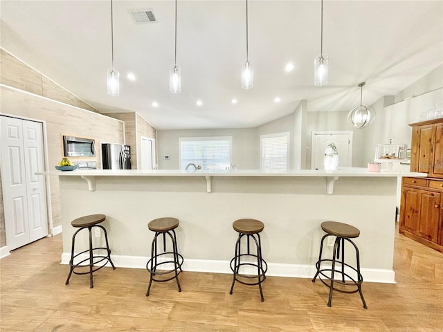 kitchen featuring visible vents, light countertops, freestanding refrigerator, and vaulted ceiling