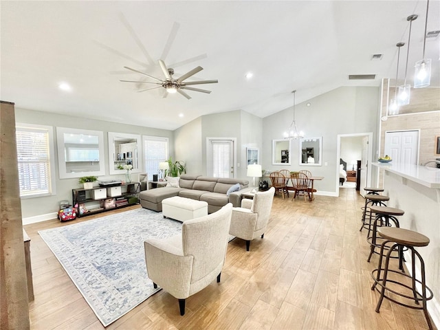 living area featuring light wood-type flooring, lofted ceiling, visible vents, and ceiling fan with notable chandelier