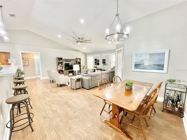 dining space featuring visible vents, ceiling fan with notable chandelier, light wood finished floors, baseboards, and vaulted ceiling