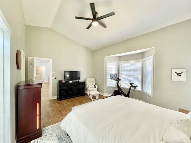 bedroom featuring lofted ceiling, wood finished floors, baseboards, and ceiling fan