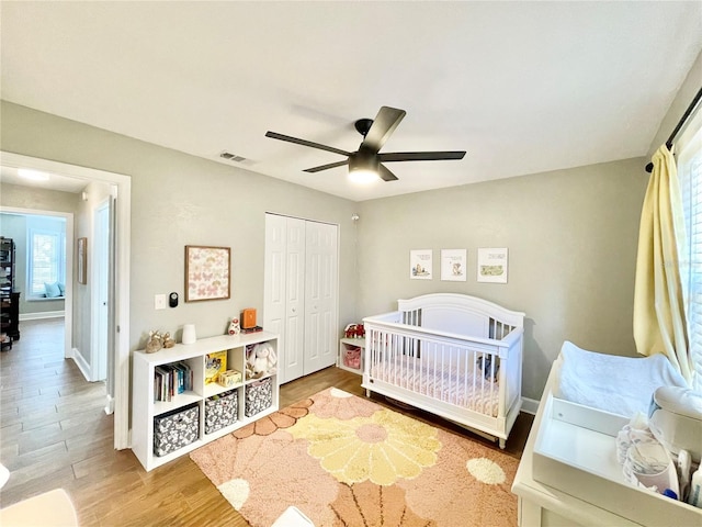 bedroom with wood finished floors, baseboards, visible vents, ceiling fan, and a closet