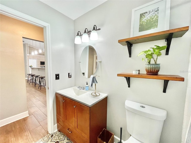 bathroom featuring vanity, toilet, wood finished floors, and baseboards