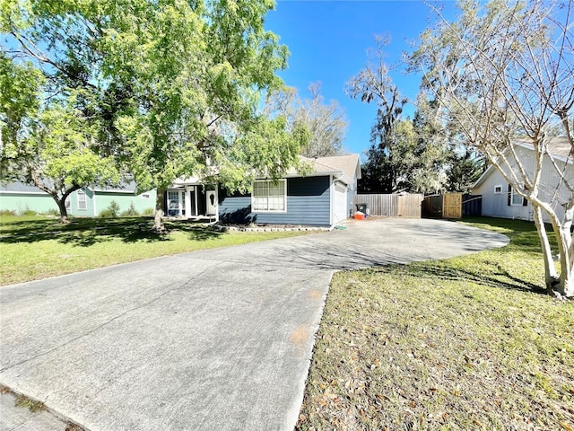 ranch-style home featuring driveway, a front lawn, and fence