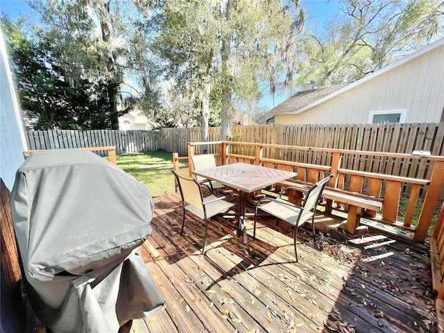 wooden terrace with outdoor dining space, a fenced backyard, a lawn, and grilling area