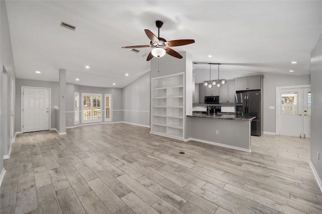 unfurnished living room with visible vents, a healthy amount of sunlight, light wood-style flooring, and vaulted ceiling