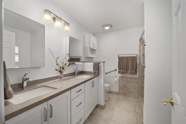 full bath with tile patterned flooring, toilet, tiled shower, and a sink