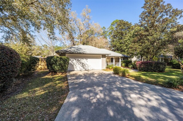 view of front facade featuring a front lawn, an attached garage, driveway, and fence