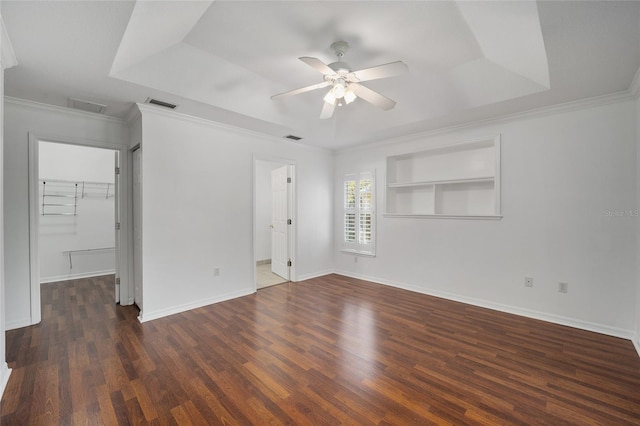 spare room with a tray ceiling, visible vents, and wood finished floors