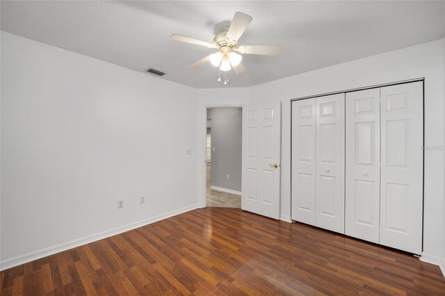 unfurnished bedroom with visible vents, dark wood-type flooring, baseboards, a closet, and a ceiling fan