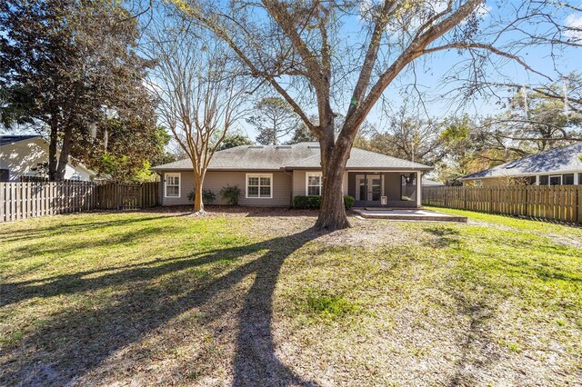 rear view of house featuring a lawn, a patio, and a fenced backyard