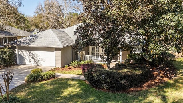 view of front of property featuring driveway, an attached garage, a porch, and a front yard