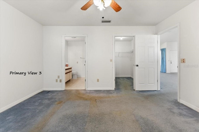 unfurnished bedroom featuring a spacious closet, visible vents, baseboards, carpet flooring, and ensuite bathroom