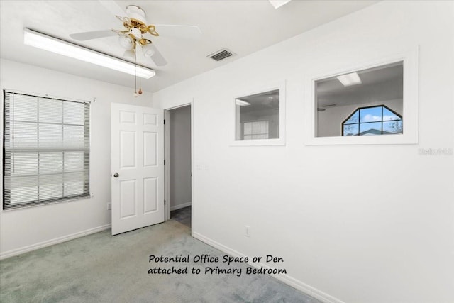 empty room featuring ceiling fan, light colored carpet, visible vents, and baseboards