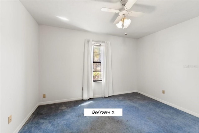 empty room with baseboards, a ceiling fan, and dark carpet