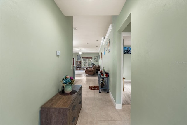 hall featuring light tile patterned floors, visible vents, and baseboards