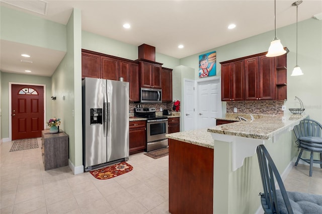 kitchen with a peninsula, open shelves, appliances with stainless steel finishes, pendant lighting, and a kitchen breakfast bar