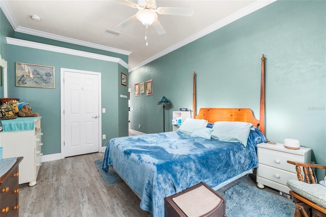 bedroom featuring baseboards, wood finished floors, visible vents, and ornamental molding