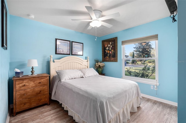 bedroom featuring light wood-style flooring, baseboards, and ceiling fan