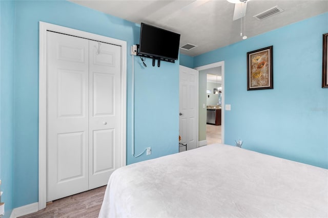 bedroom featuring a ceiling fan, wood finished floors, visible vents, and a closet