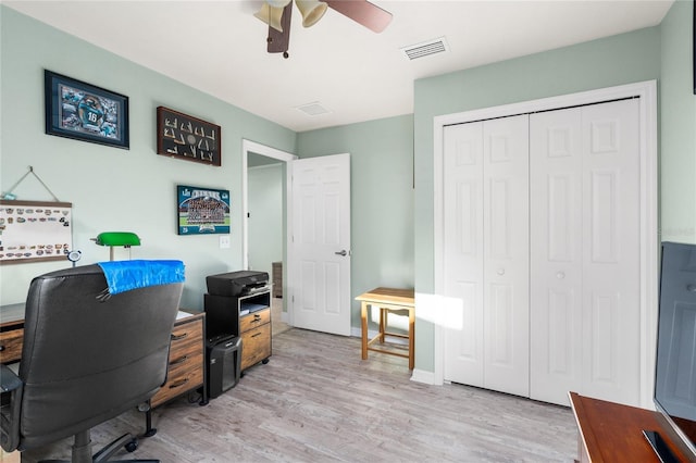 office featuring light wood-type flooring, baseboards, visible vents, and a ceiling fan