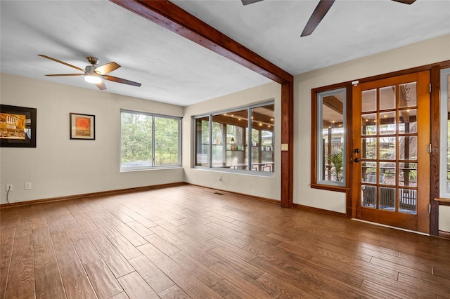 unfurnished room featuring beam ceiling, ceiling fan, and wood finished floors