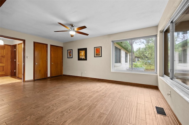 unfurnished bedroom featuring light wood finished floors, visible vents, two closets, and baseboards