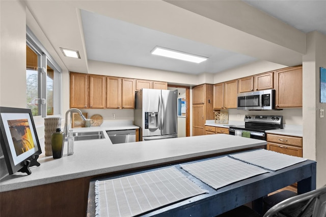 kitchen featuring a peninsula, stainless steel appliances, light countertops, and a sink