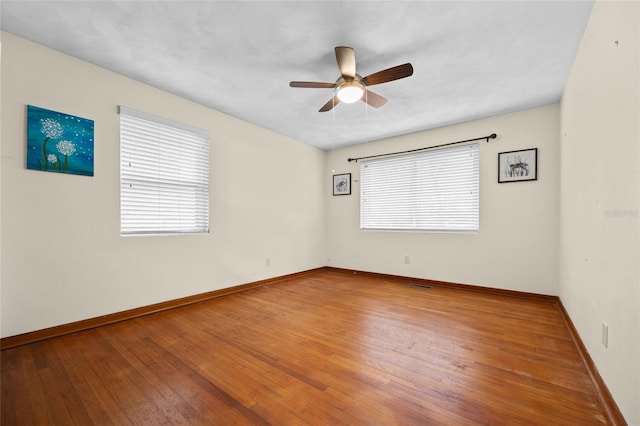 unfurnished room featuring hardwood / wood-style floors, a ceiling fan, and baseboards