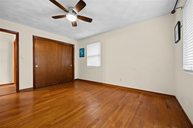 unfurnished bedroom with hardwood / wood-style flooring, baseboards, a closet, and ceiling fan