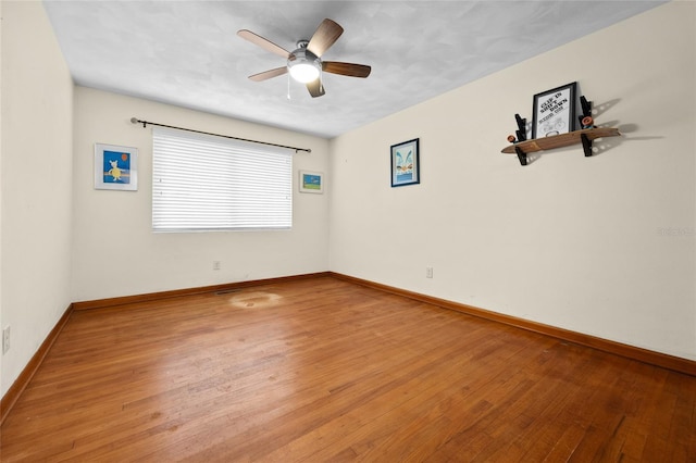 unfurnished room featuring a ceiling fan, baseboards, and hardwood / wood-style flooring