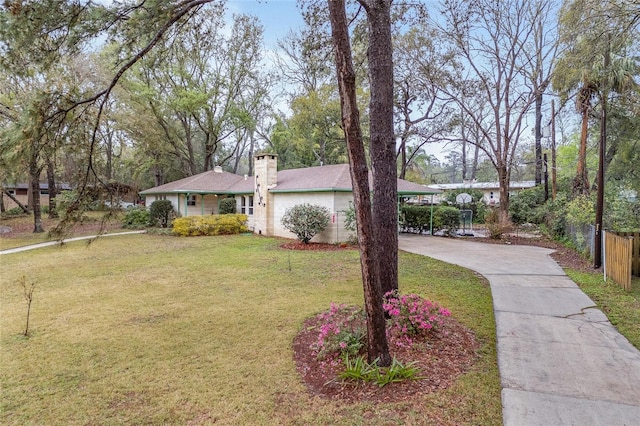 ranch-style house featuring a chimney, concrete driveway, a front yard, and fence