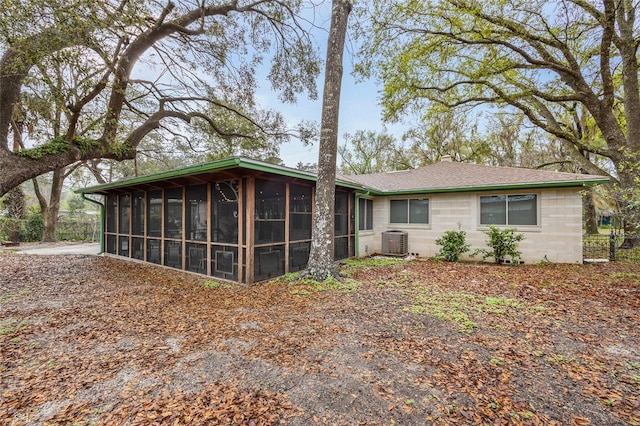 view of front of house with a sunroom, fence, central AC, and a chimney