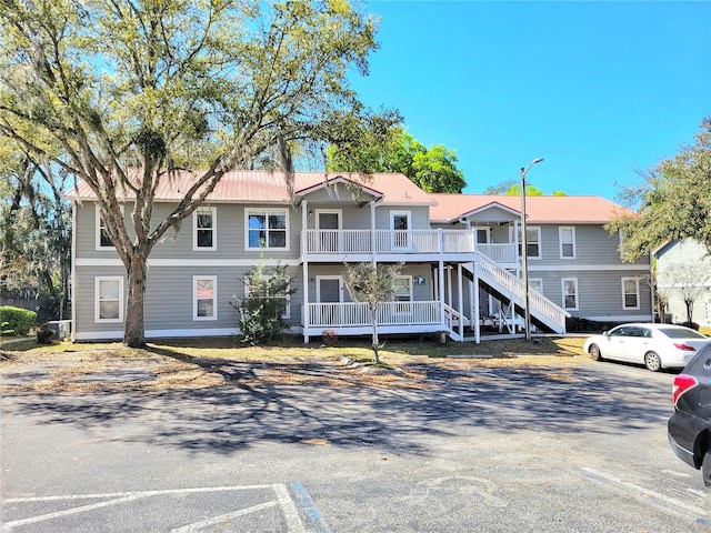 view of front of property with metal roof, uncovered parking, and stairs